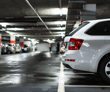A white car is parked in a dimly lit parking garage.